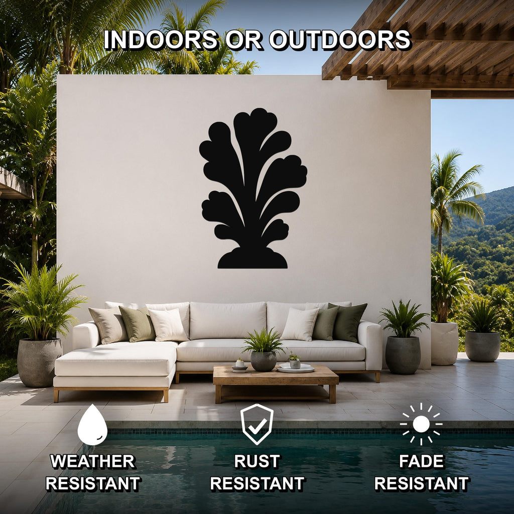Black metal coral wall art with layered leaf cutouts, mounted on a white outdoor wall above a sofa in a patio living area.