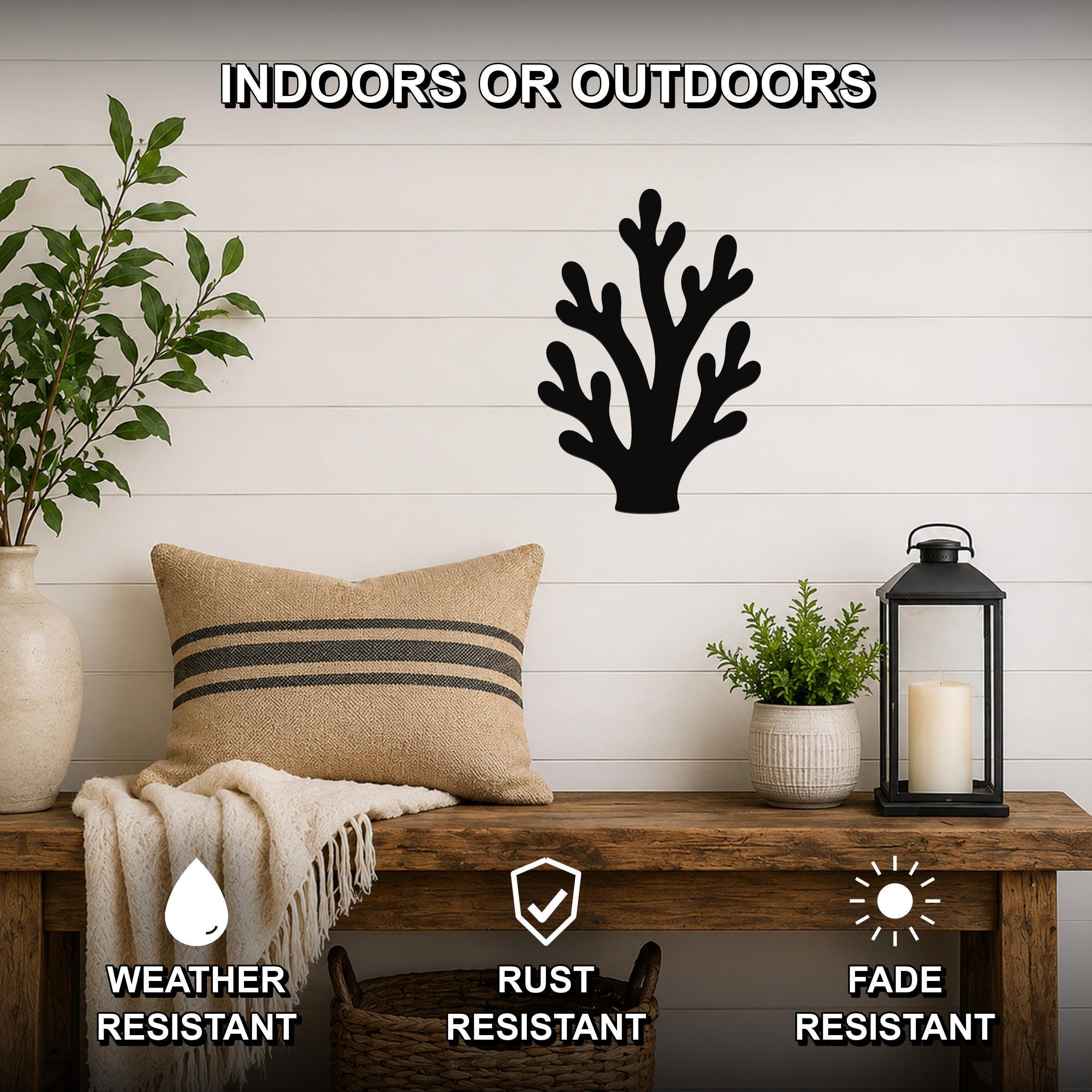 Black metal branching coral wall art with cutout design, mounted on a shiplap wall above a wooden bench in a coastal-style entryway.