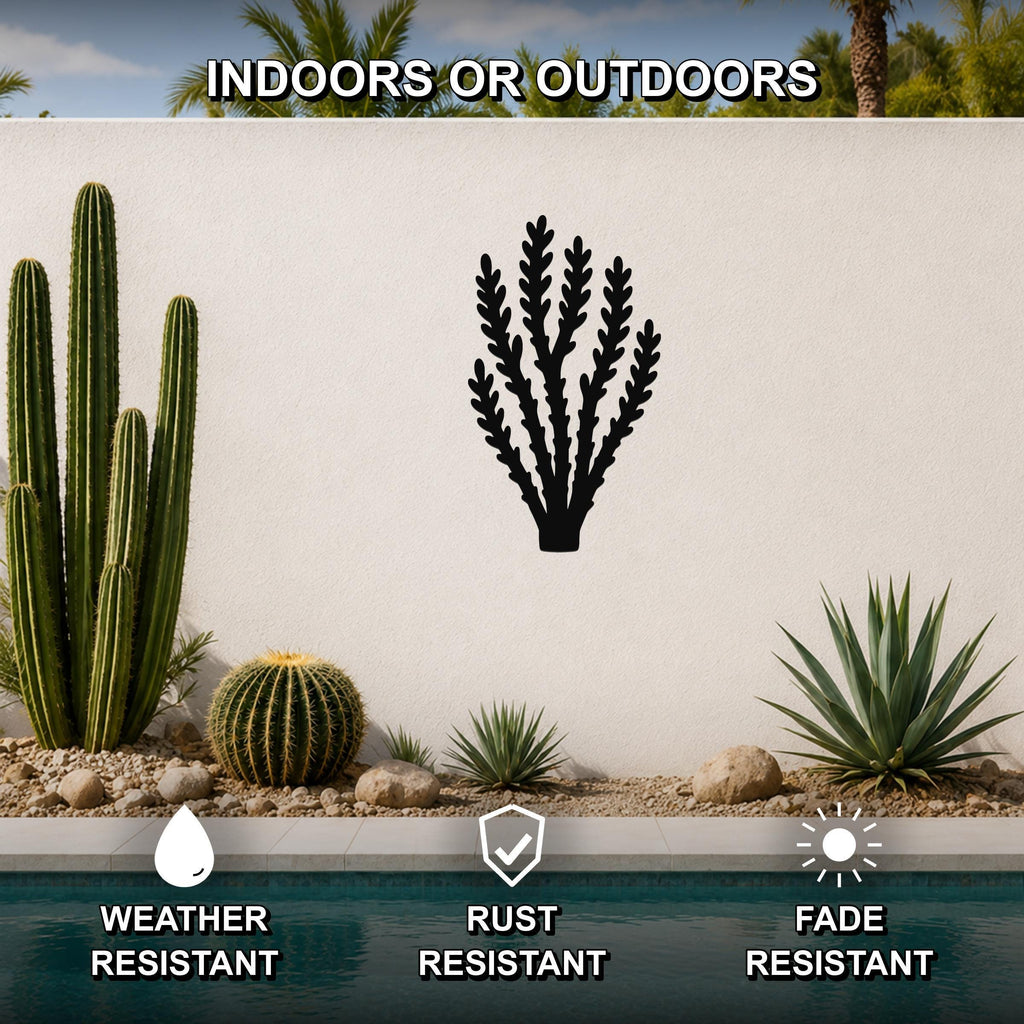 Black metal desert branch wall art with leafy cutouts, mounted on a white outdoor wall above a pool, shown in a desert garden setting.