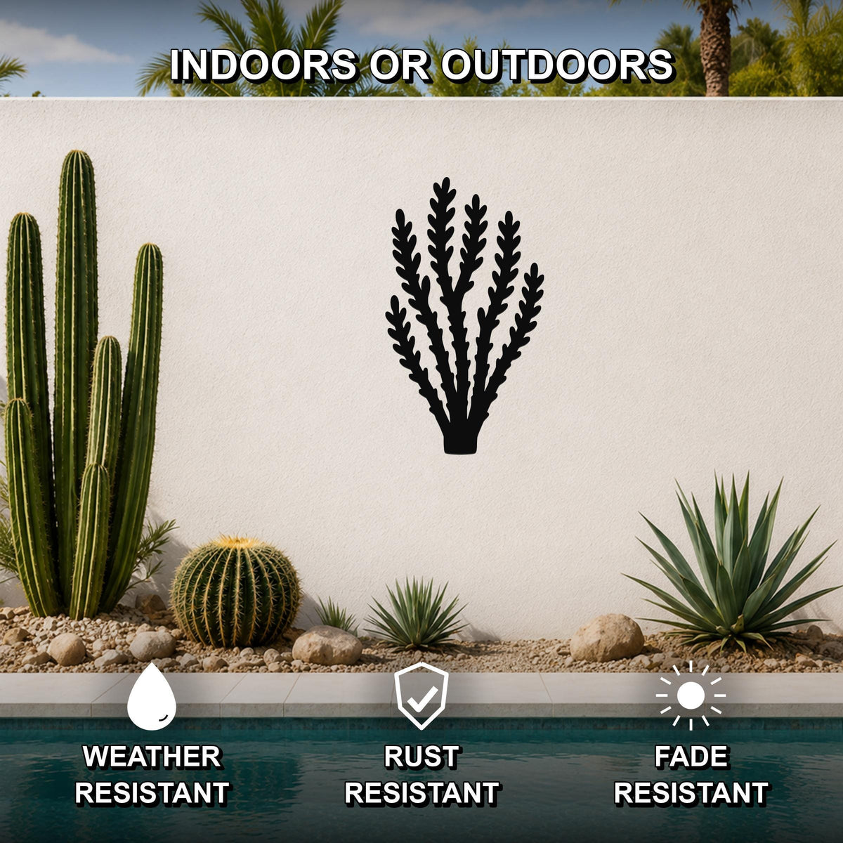 Black metal desert branch wall art with leafy cutouts, mounted on a white outdoor wall above a pool, shown in a desert garden setting.