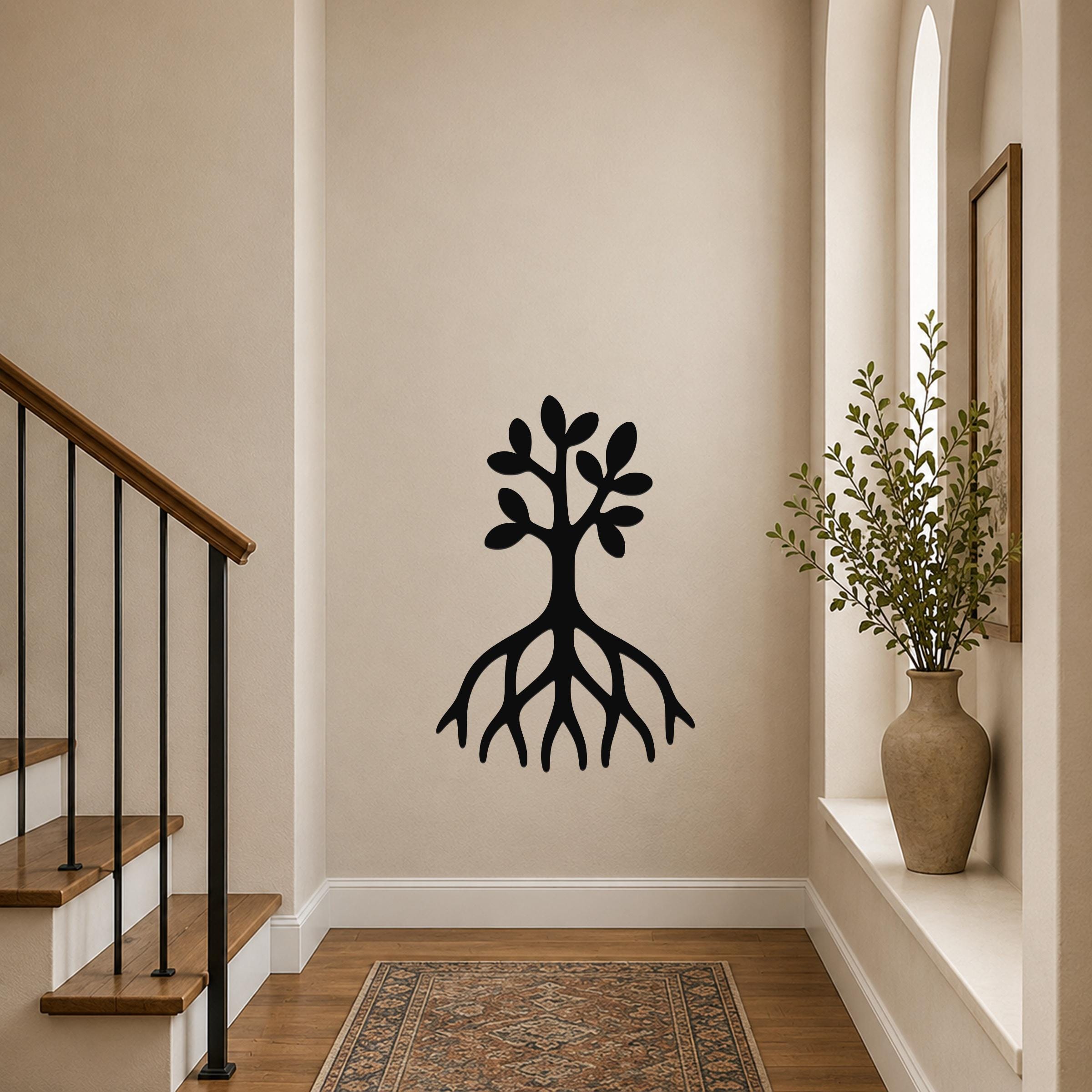 Black metal wall art cutout of a tree with roots and leaves, mounted on a hallway wall above a patterned rug near a staircase.