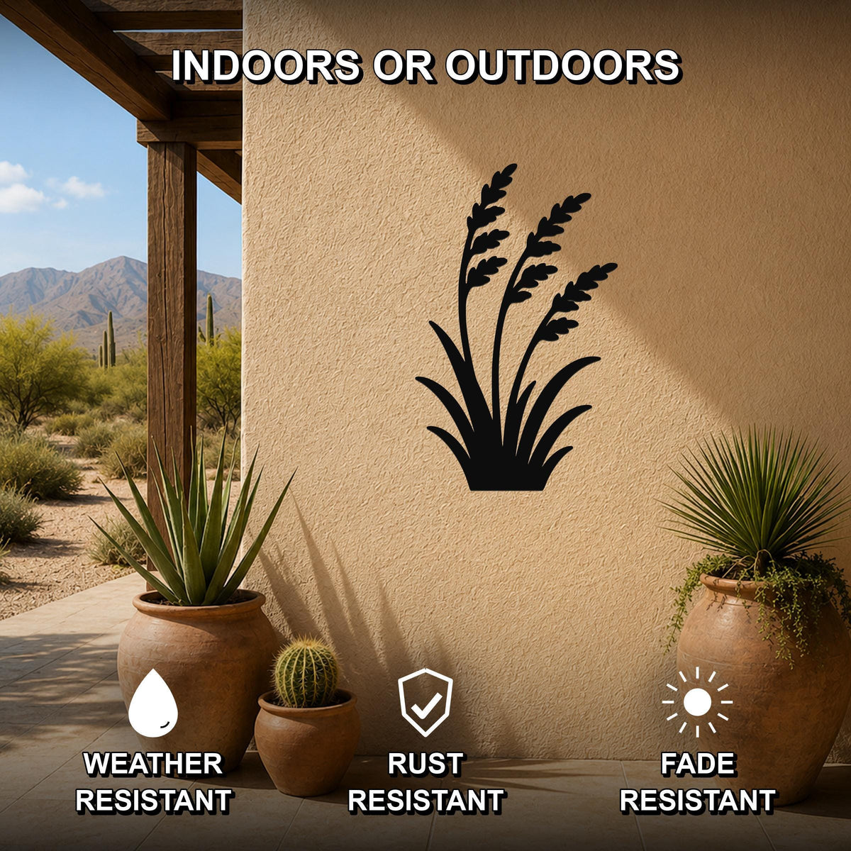 Black metal wild grass wall art silhouette mounted on a beige outdoor wall, displayed on a patio with potted plants and desert scenery in the background.