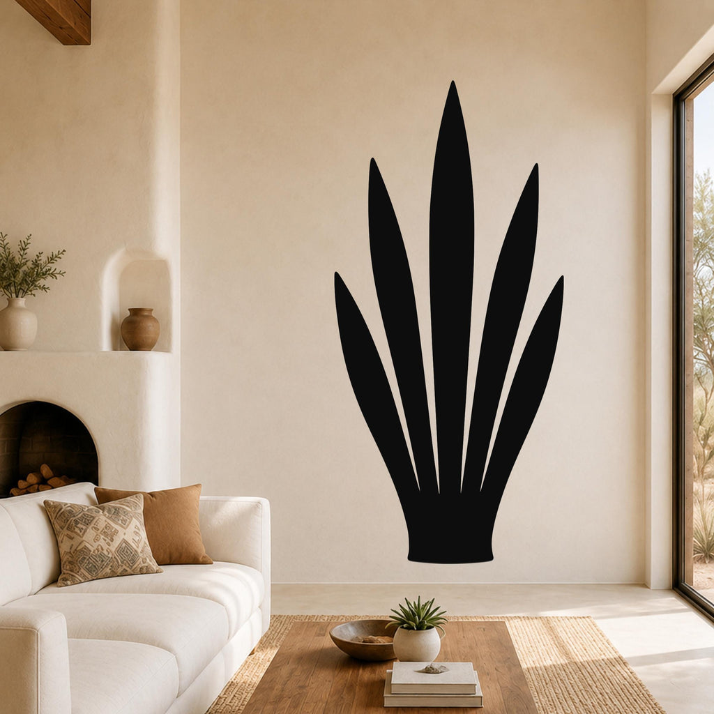 Black metal agave plant wall art with leaf cutouts, mounted on a living room wall above a sofa.