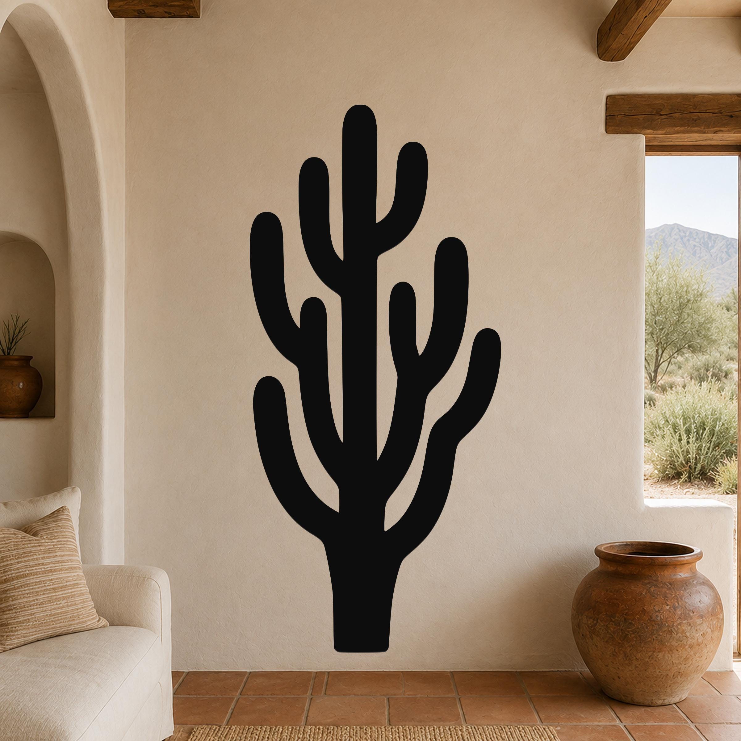 Black metal saguaro cactus wall art with branching cutouts, mounted on a stucco wall in a southwestern-style living room.