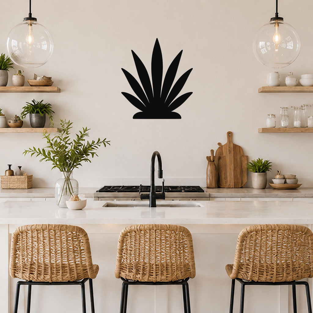 Black metal agave wall art silhouette mounted on a kitchen wall above a counter, with wicker bar stools and pendant lights visible below.