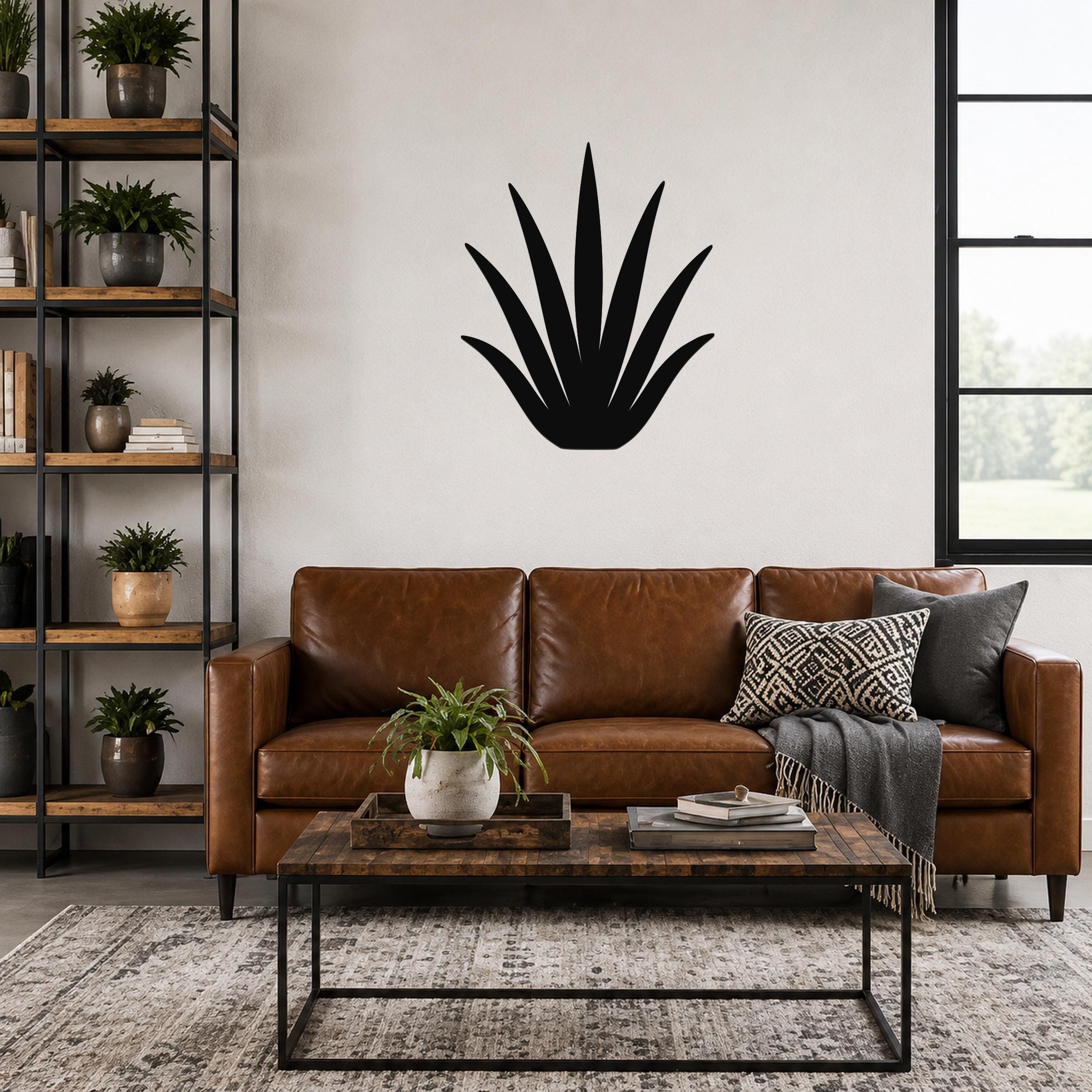 Black metal aloe vera wall art silhouette with spiky leaves, mounted above a brown leather sofa in a living room.