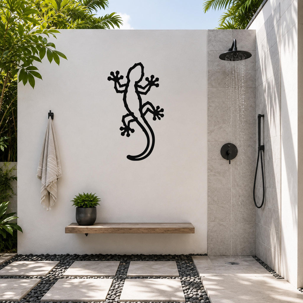 Black metal lizard wall art with cutout details, mounted on a white outdoor wall above a wooden bench in a patio shower area.