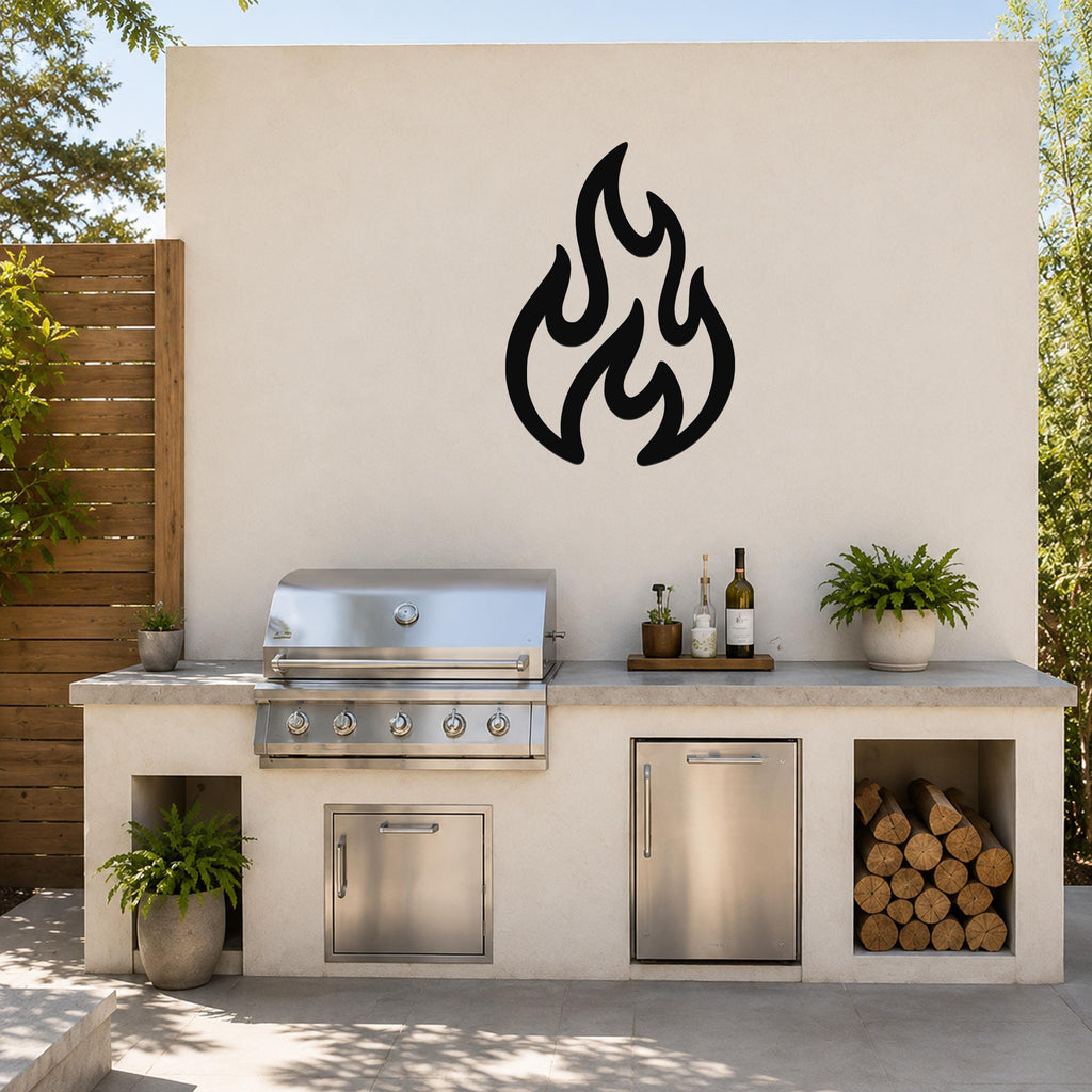 Black metal flame wall art with flowing, abstract cutout shapes, mounted on an outdoor kitchen wall above a stainless steel grill.
