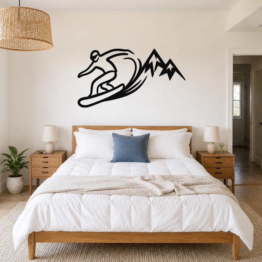 Black metal wall art silhouette of a snowboarder carving through a wave with mountain peaks, mounted above a bed in a bedroom.