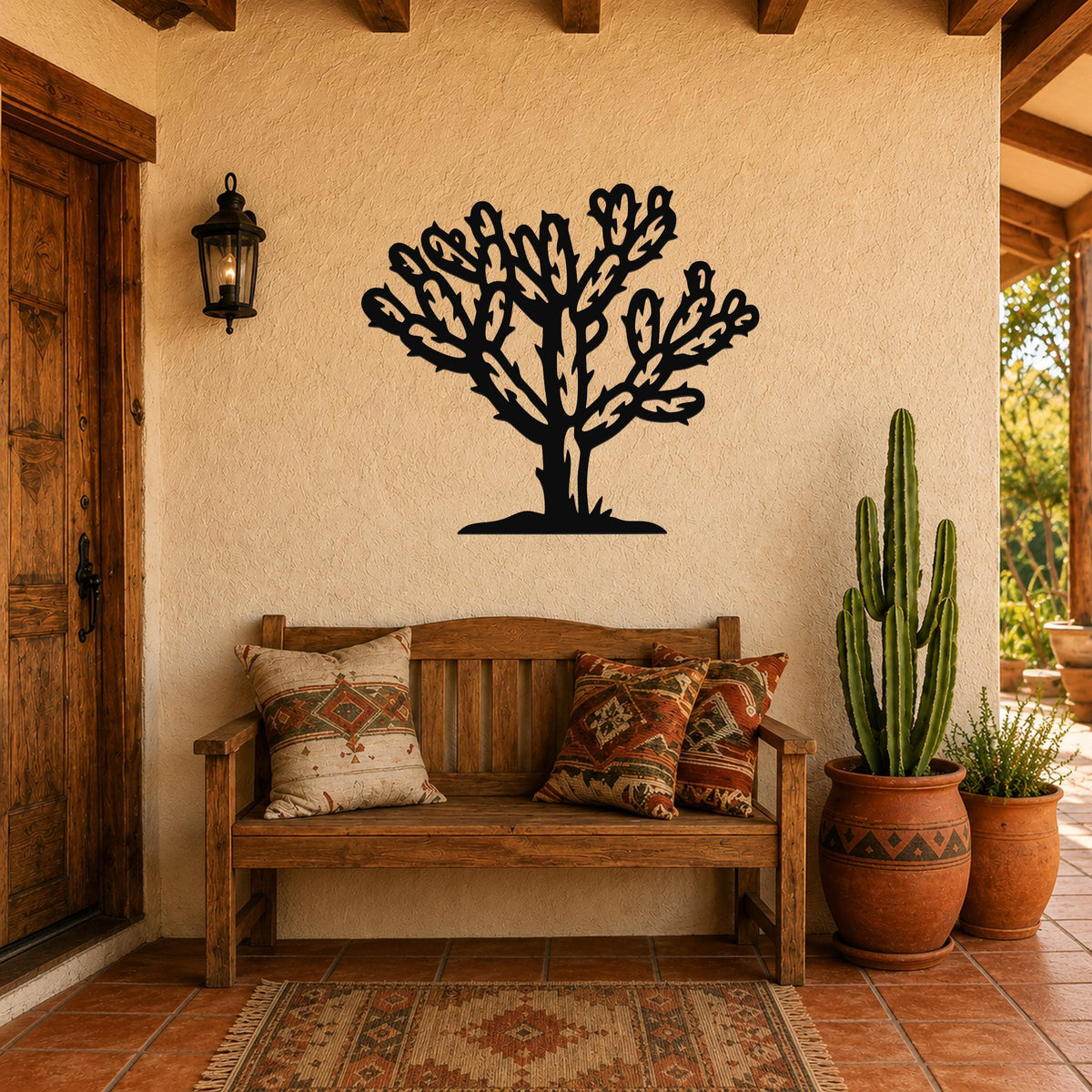 Black metal Cholla cactus wall art with intricate branch cutouts, mounted on a stucco wall above a wooden bench in a patio entryway.