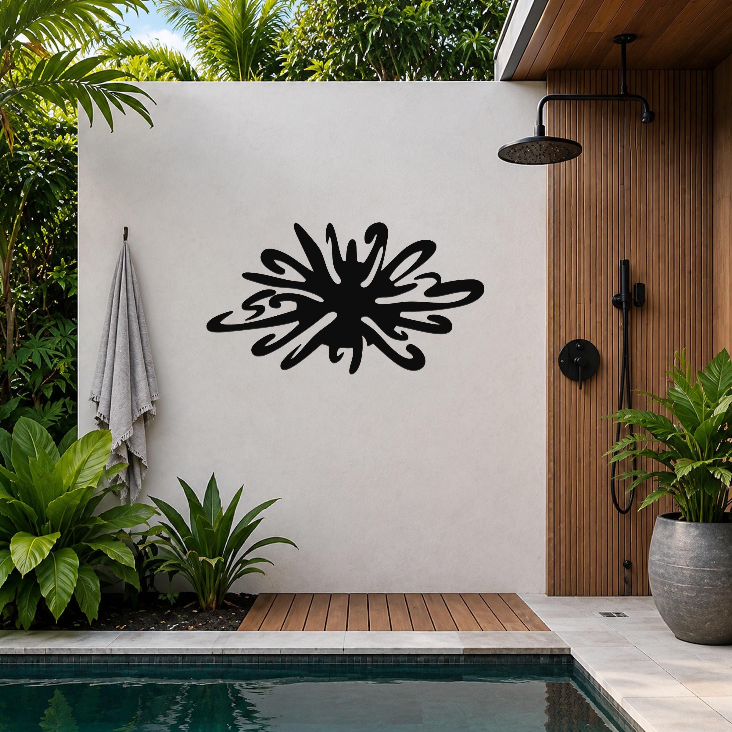 Black metal sea urchin wall art with organic spines and cutout details, mounted on a white outdoor wall beside a wooden shower and pool area.