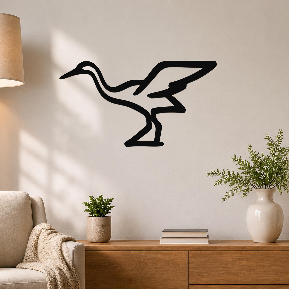 Black metal crane wall art silhouette mounted on a light-colored wall above a wooden console table in a living room.