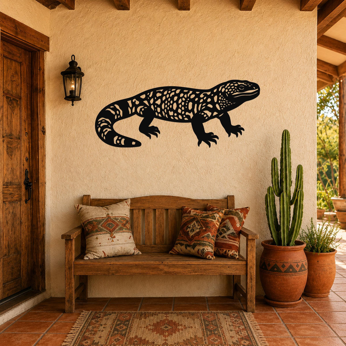 Black metal wall art of a Gila monster with intricate cutout patterns, mounted on a stucco wall above a wooden bench in a patio entryway.