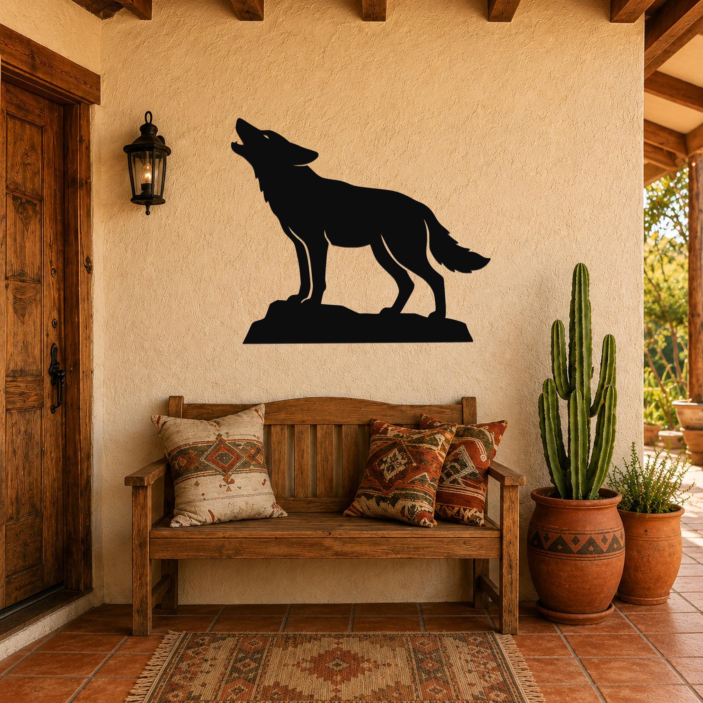 Black metal coyote wall art in a howling silhouette, mounted on a stucco wall above a wooden bench in a rustic patio entry.
