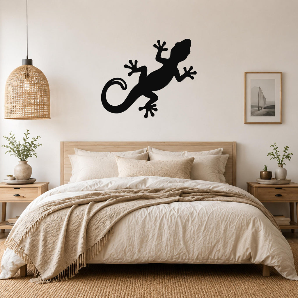 Black metal gecko wall art silhouette mounted above a bed in a neutral bedroom.