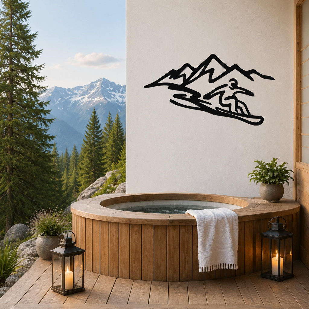 Black metal wall art silhouette of a snowboarder in motion against a mountain range, mounted on a white wall above a wooden hot tub on a deck with a mountain view.