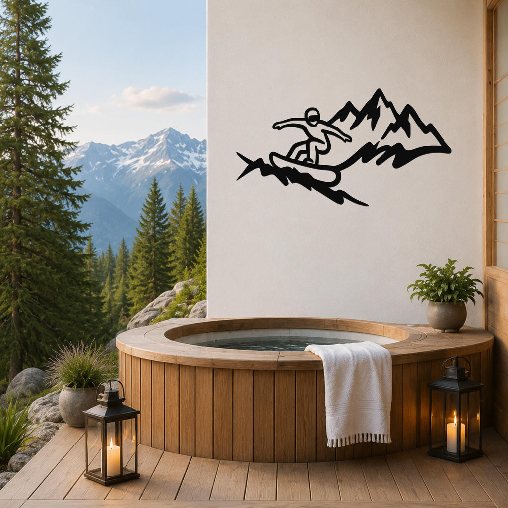 Black metal wall art featuring a snowboarder silhouette in motion above mountain peaks, mounted on a white wall above a wooden hot tub on a deck with a mountain view.