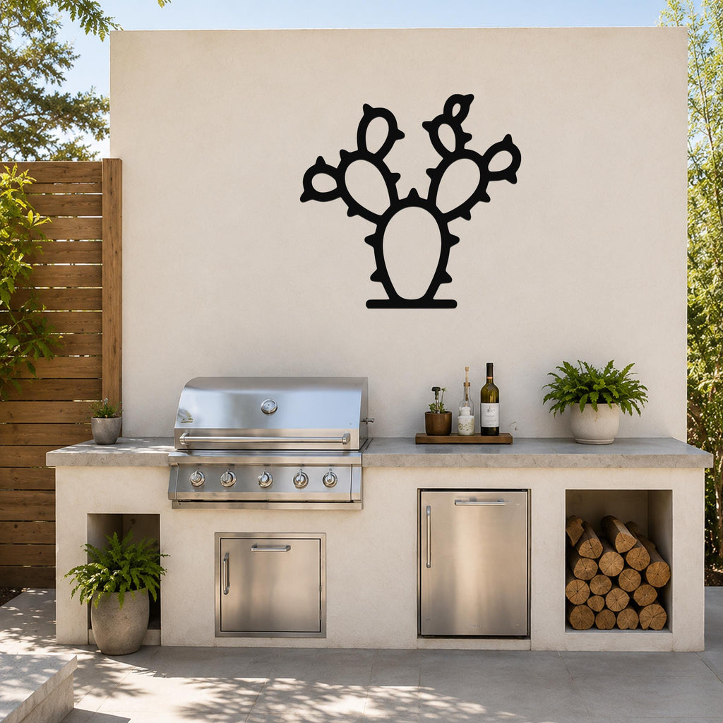 Black metal cactus wall art with a silhouette cutout of a prickly pear, mounted on a light-colored outdoor wall above a kitchen counter.