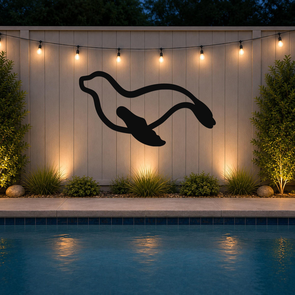 Black metal sea lion wall art with motion-line cutouts, mounted on a light-colored outdoor wall above a pool at night.