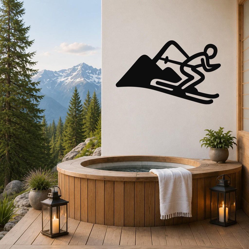 Black metal skier and mountain wall art silhouette mounted on a white wall above a wooden hot tub on a deck with a mountain view.