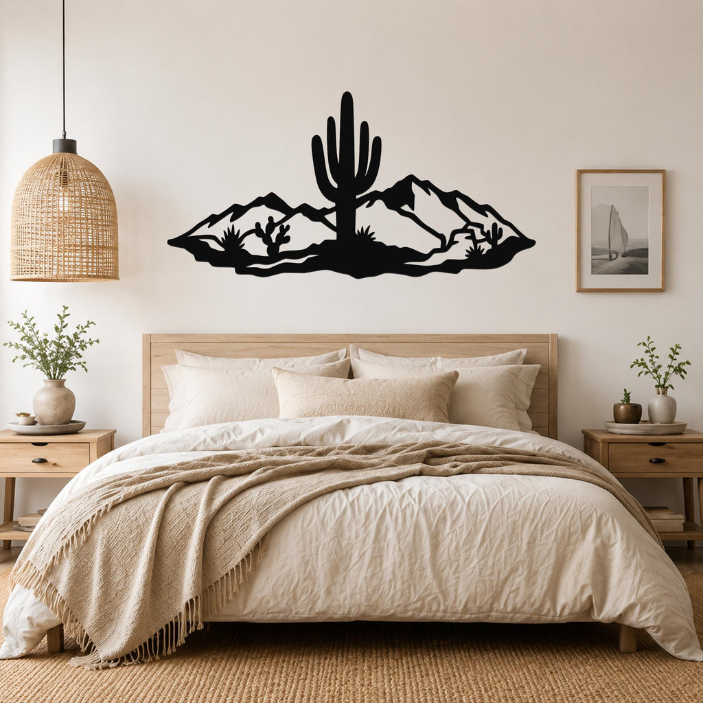 Black metal wall art silhouette of a saguaro cactus and desert mountains, mounted above a bed in a neutral bedroom.
