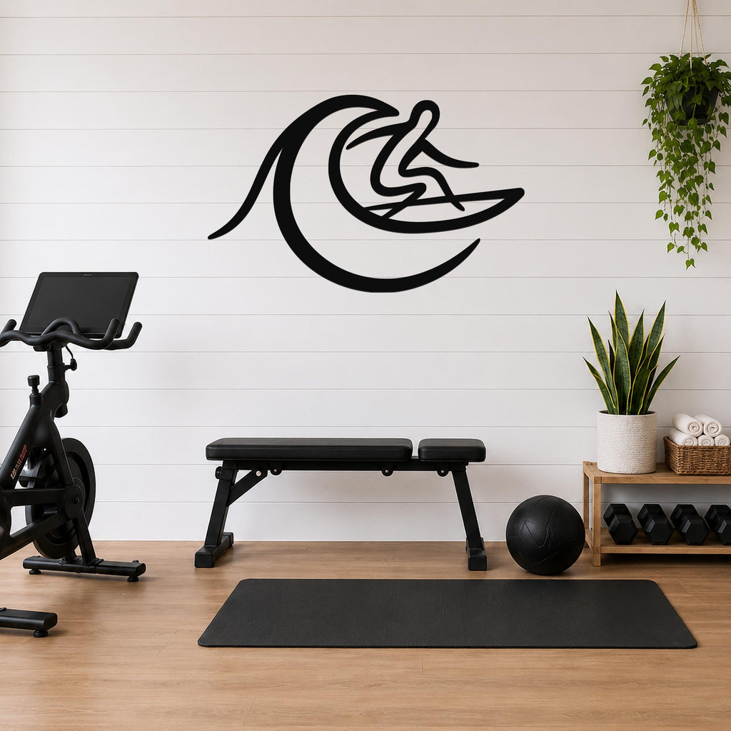 Black metal surfer wall art with wave cutout, mounted on a white shiplap wall above a workout bench in a home gym.