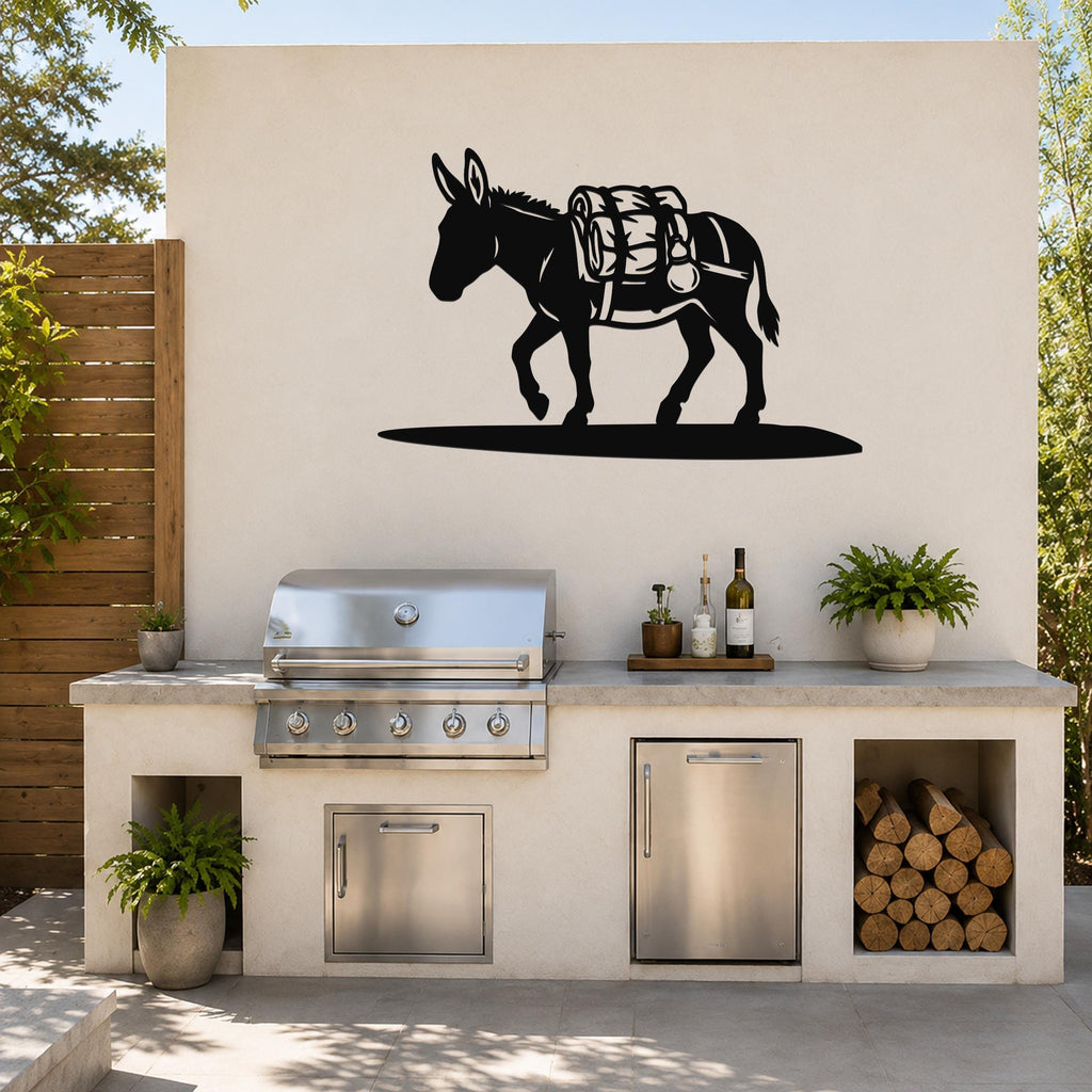 Black metal burro wall art with saddle and gear cutouts, mounted on an outdoor kitchen wall above a grill.