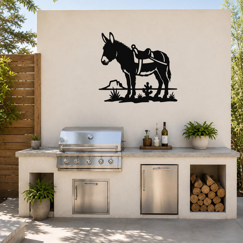Black metal wall art silhouette of a burro with saddle and desert plants, mounted on an outdoor kitchen wall above a stainless steel grill.