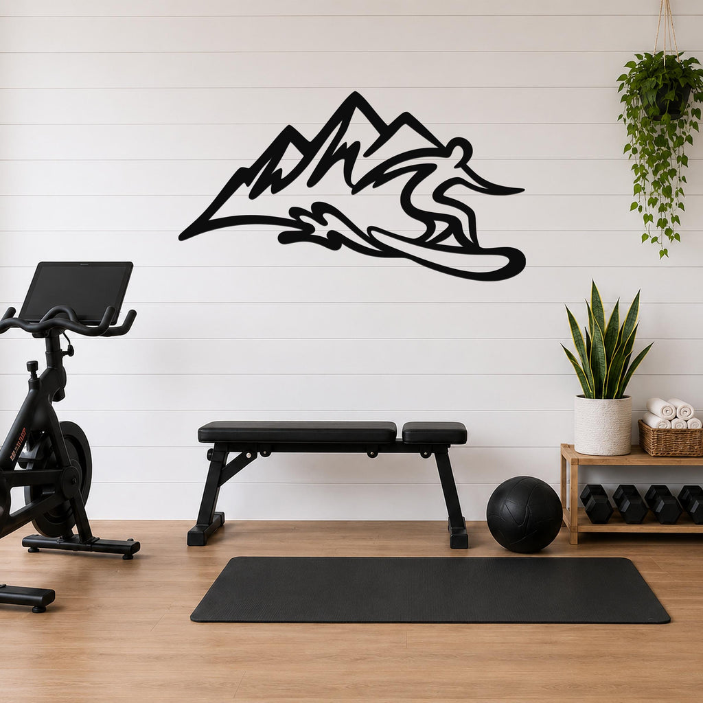 Black metal wall sculpture of a snowboarder in motion above a mountain range, mounted on a white shiplap wall above a workout bench in a home gym.