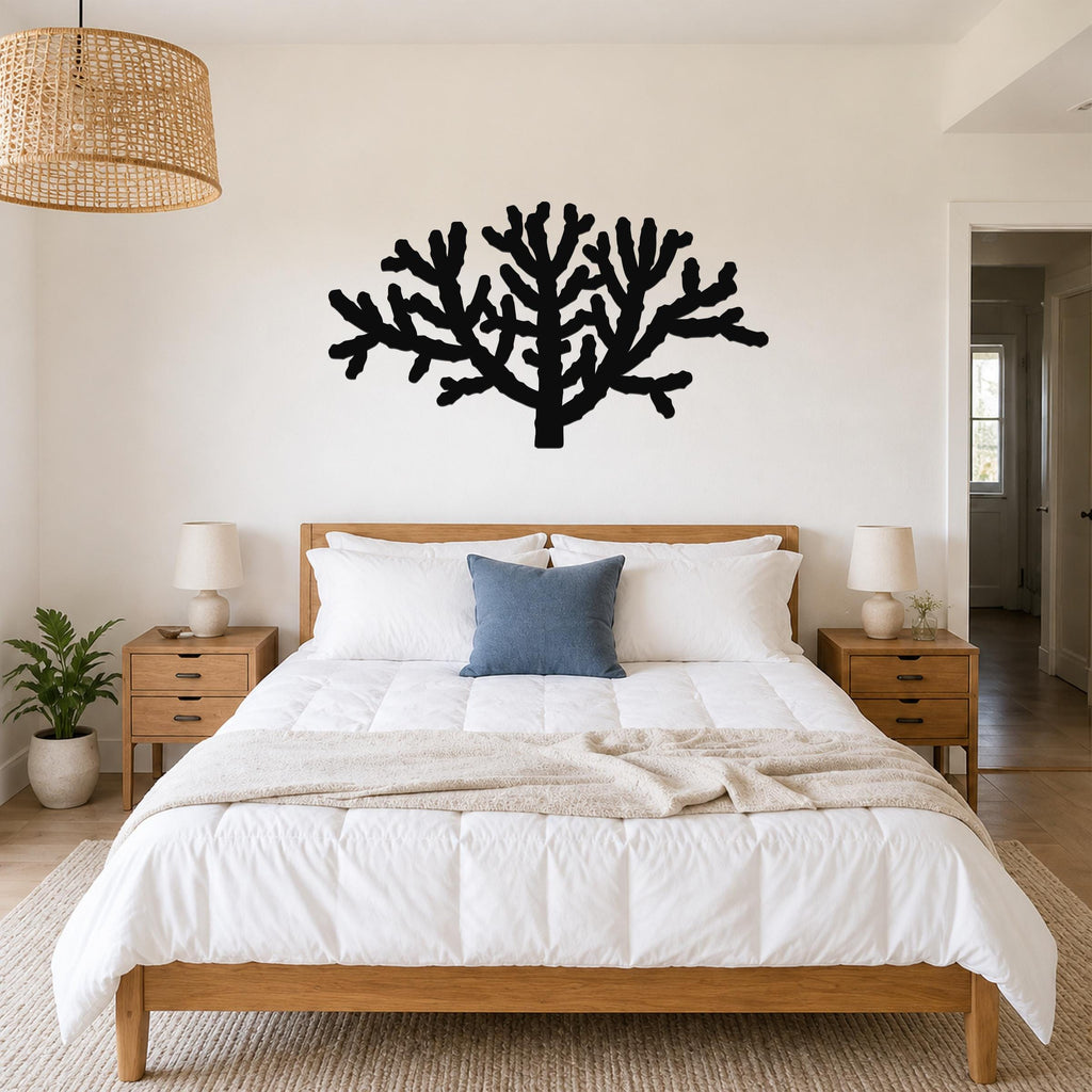 Black metal Cholla cactus wall art silhouette mounted above a bed in a bedroom.