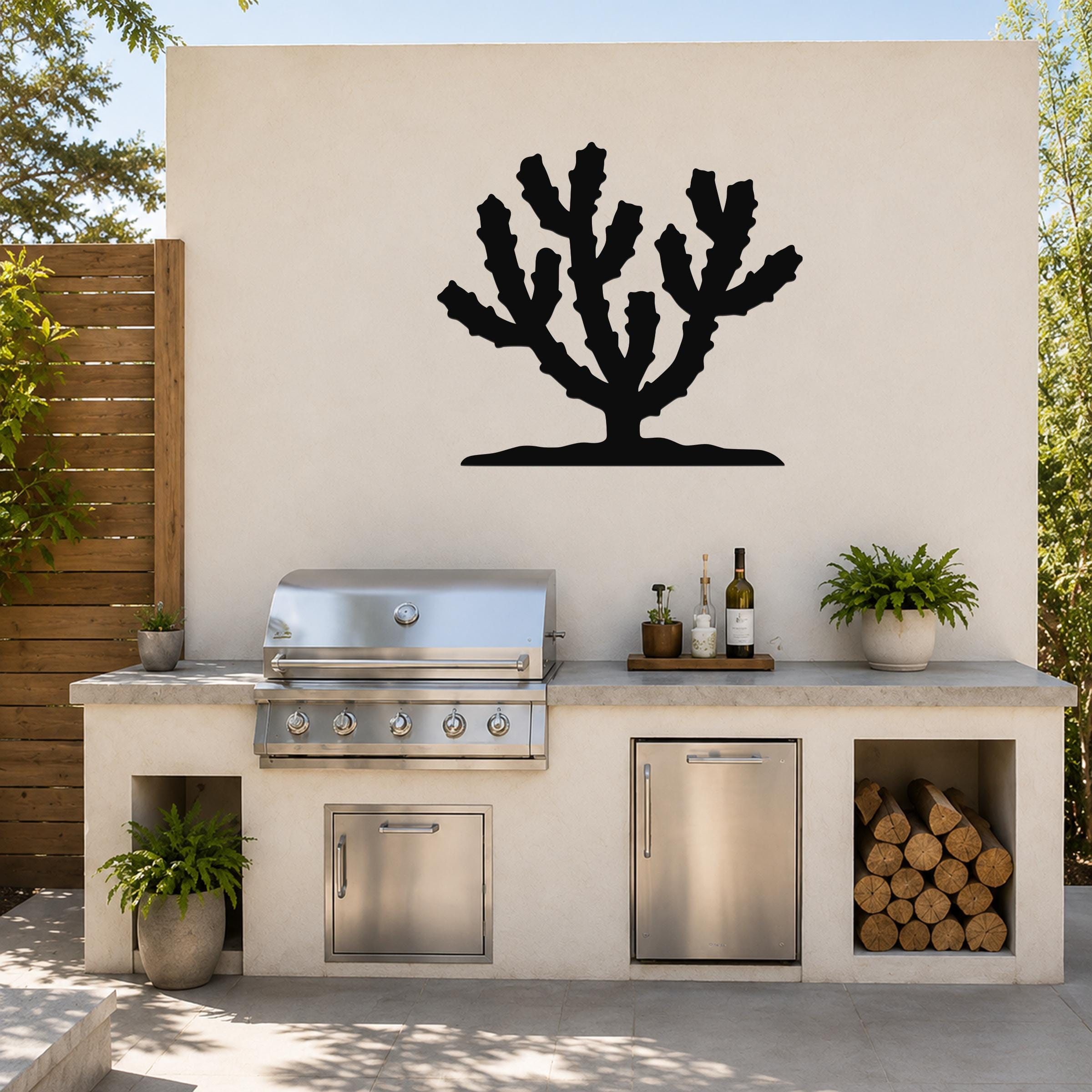 Black metal Cholla cactus wall art silhouette mounted on an outdoor patio wall above a built-in grill and counter.