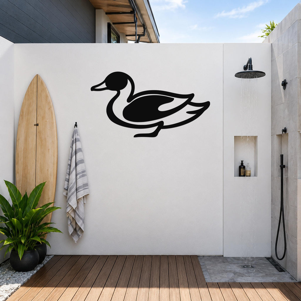 Black metal duck wall sculpture with a silhouette design, mounted on a white outdoor wall above a wooden deck near a shower area.