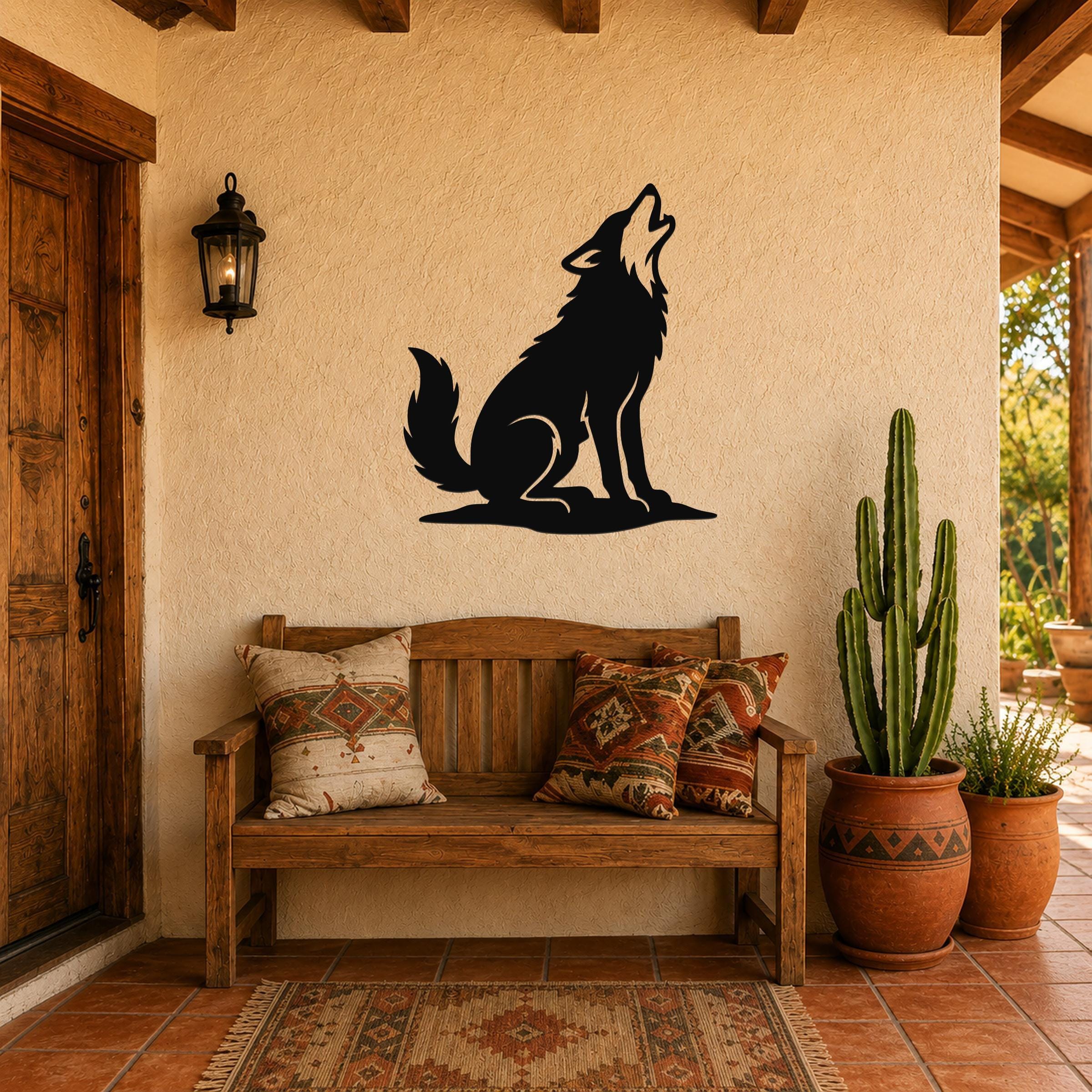 Black metal coyote wall art in a howling silhouette, mounted on a stucco wall above a wooden bench in a southwestern-style entryway.