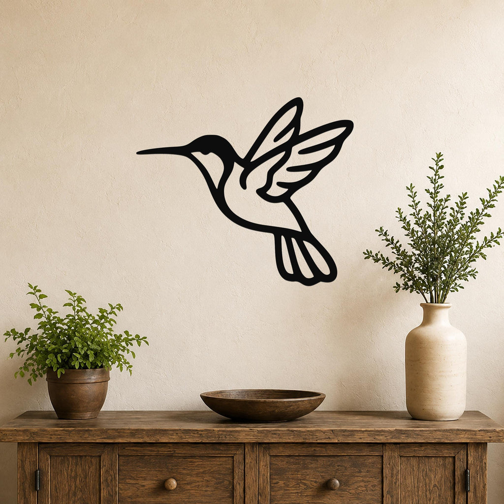 Black metal hummingbird wall art with wing and tail cutouts, mounted on a beige wall above a wooden console table.