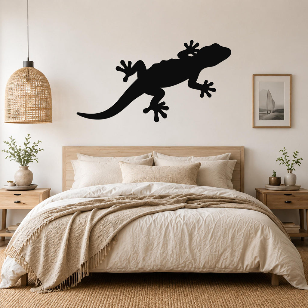 Black metal lizard wall art silhouette mounted above a bed in a neutral bedroom.
