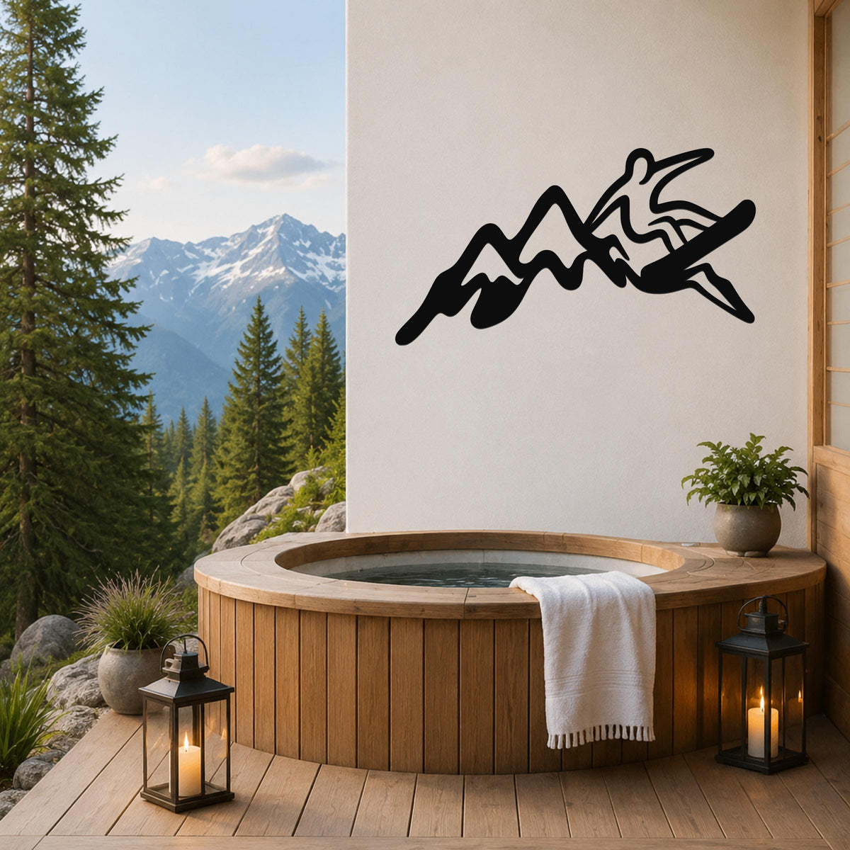 Black metal wall art featuring a snowboarder silhouette over mountain peaks, mounted on a white wall above a wooden hot tub on a deck with a mountain view.