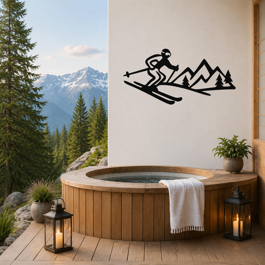 Black metal wall art of a skier and mountain silhouette, mounted on a white wall above a wooden hot tub on a deck with a mountain view.