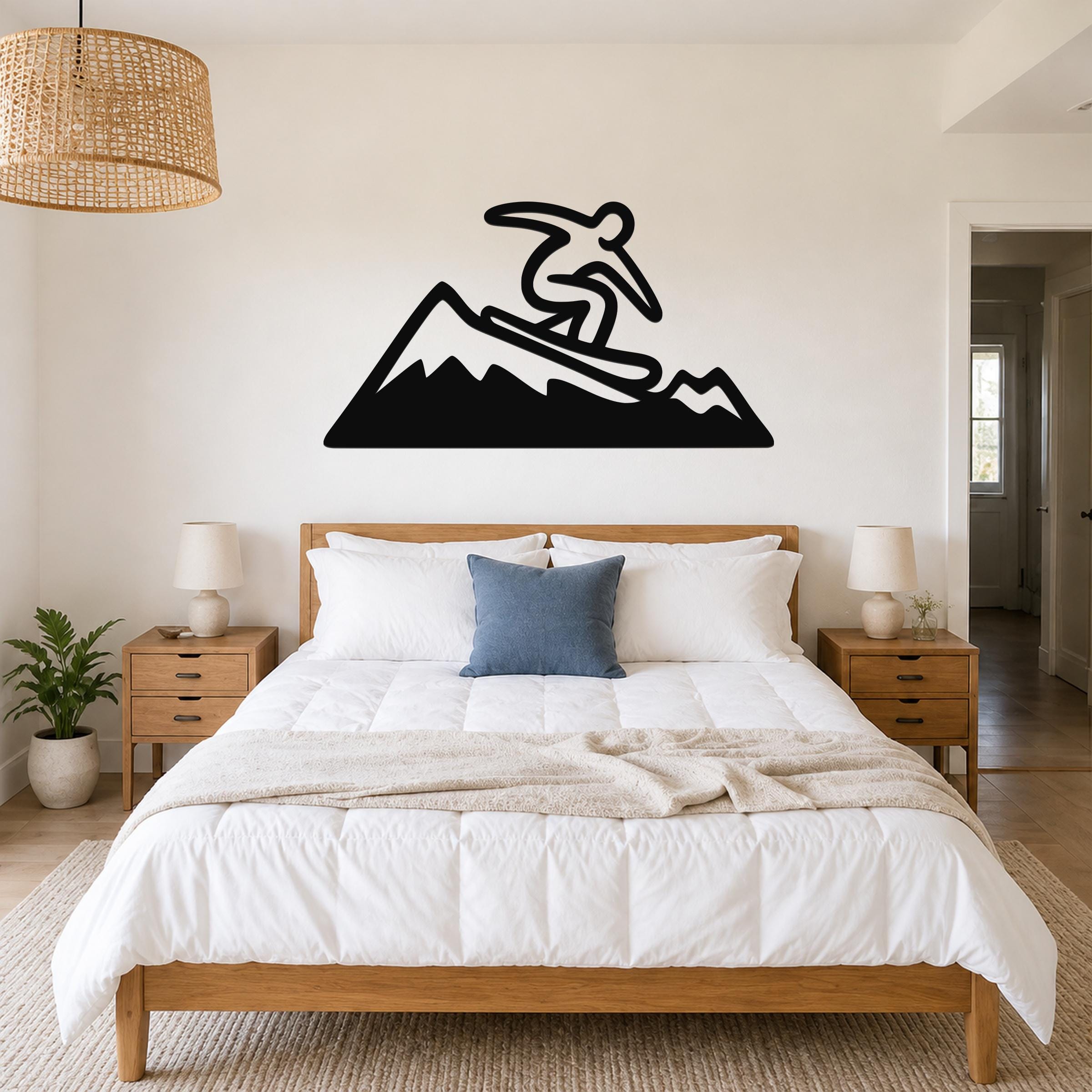 Black metal wall art silhouette of a snowboarder on a mountain, mounted above a bed in a bedroom.