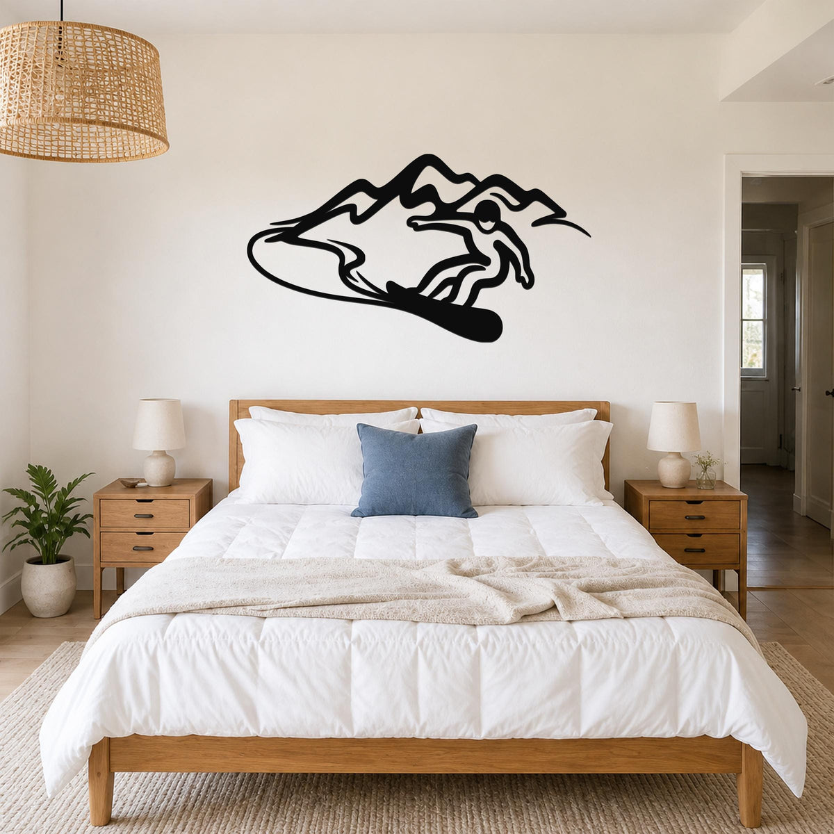 Black metal wall art silhouette of a snowboarder in motion above a bed in a bedroom.
