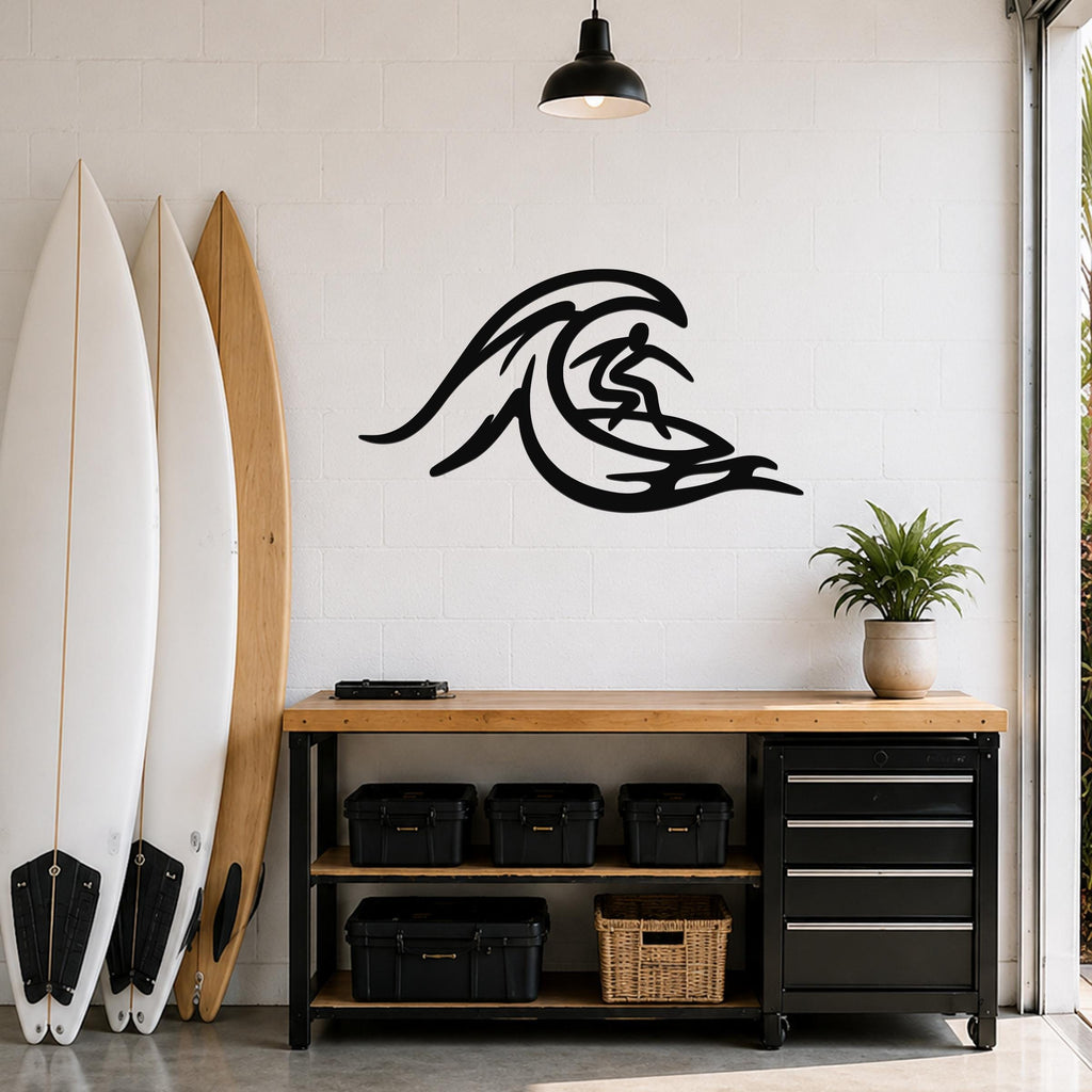 Black metal surfer wall art with wave cutout design, mounted on a white brick wall above a wooden workbench in a garage.