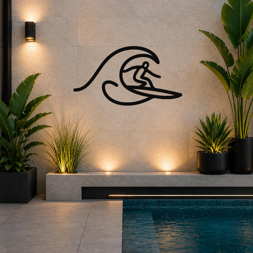 Black metal wall art silhouette of a surfer riding a wave, mounted on a tiled wall above a poolside planter in a modern outdoor space.