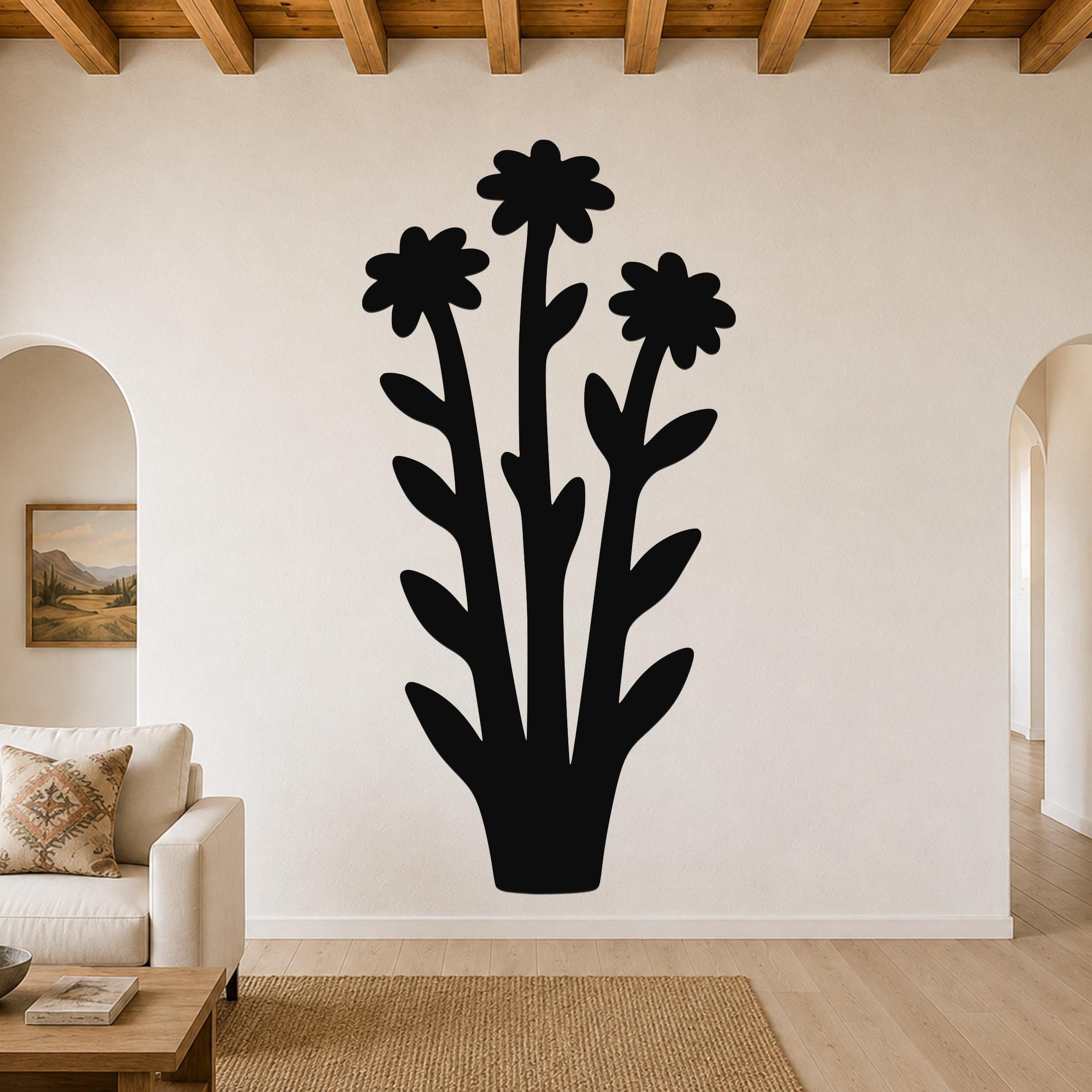 Black metal wall art silhouette of a wildflower bouquet with three flowers and leaves, mounted on a living room wall above a sofa.