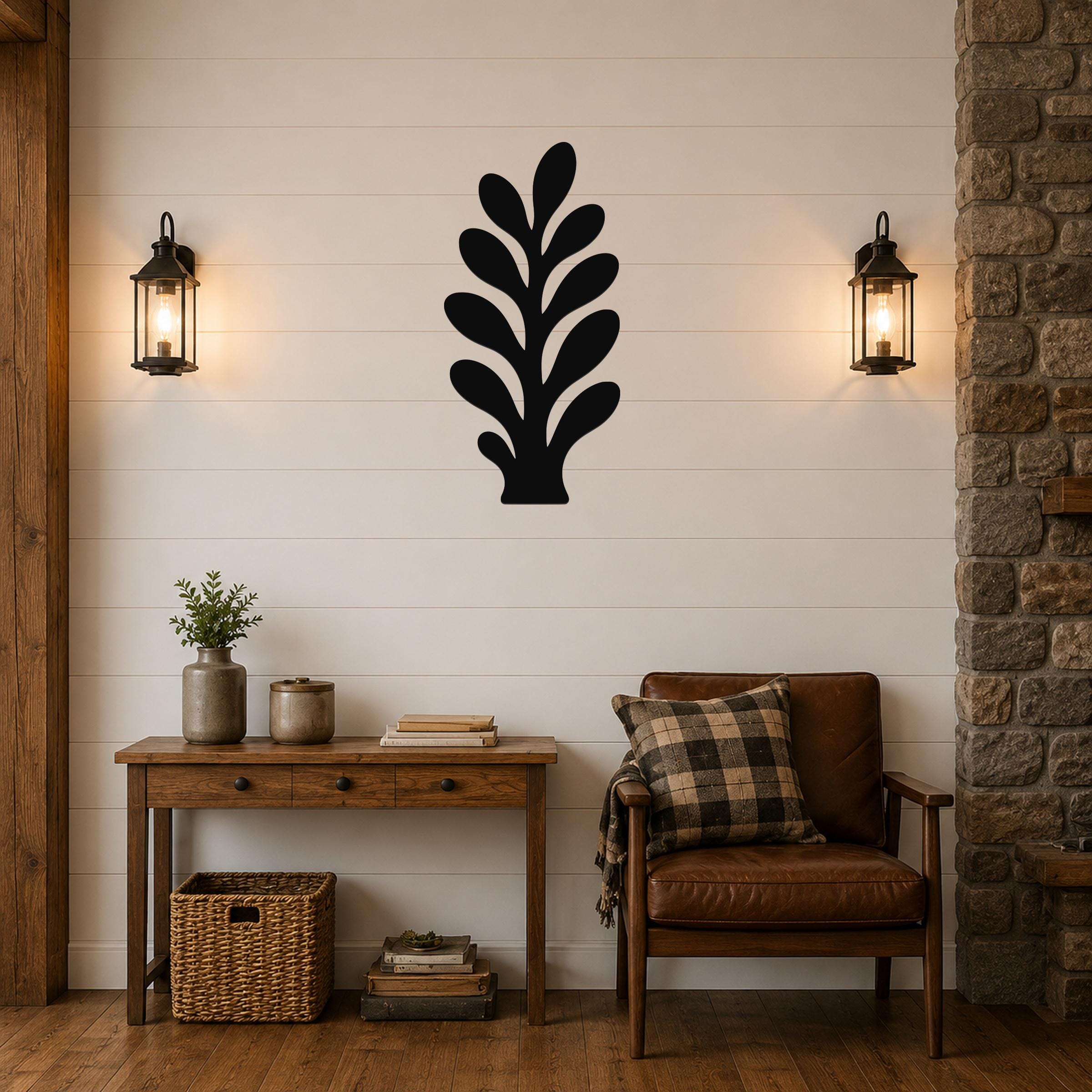 Black metal wall art in a leafy sprig silhouette, mounted on a shiplap wall above a wooden console table in a living room.