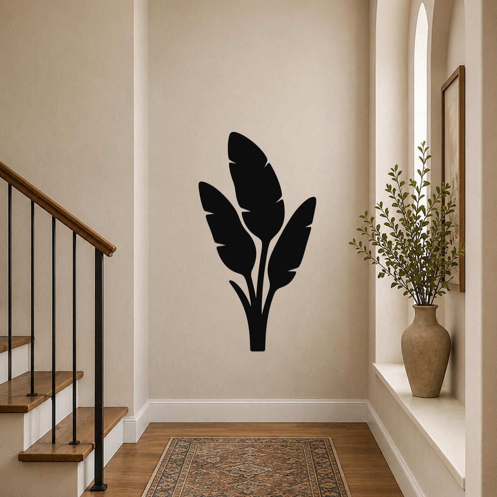 Black metal wall art with a tropical leaf silhouette, mounted on a hallway wall above a patterned rug near a staircase.