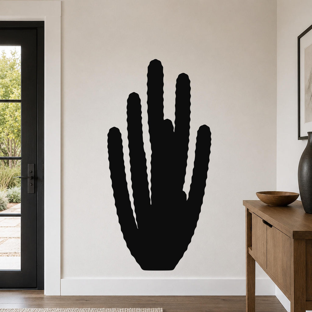 Black metal wall art in the silhouette of an organ pipe cactus with vertical ridges, mounted on a light-colored wall in a living room.
