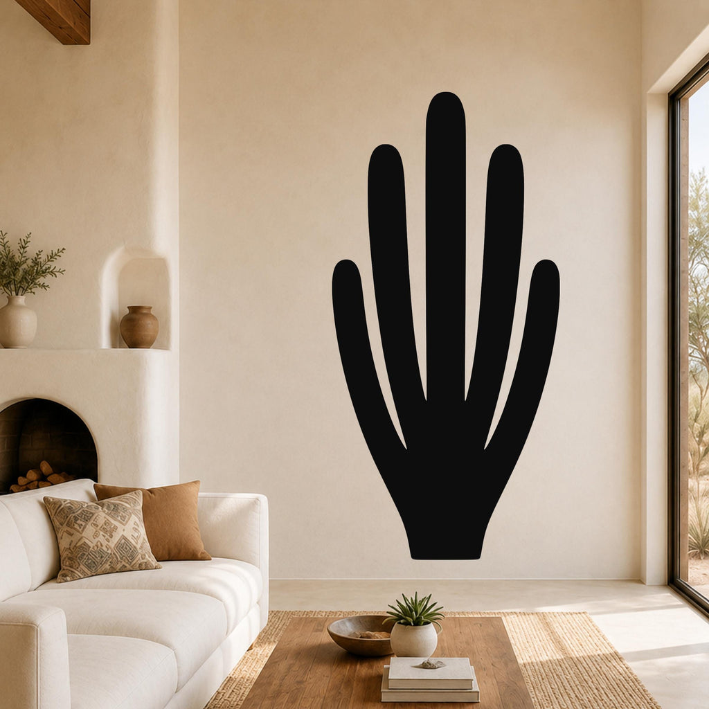 Black metal wall art in the shape of an organ pipe cactus, mounted on a living room wall above a white sofa.