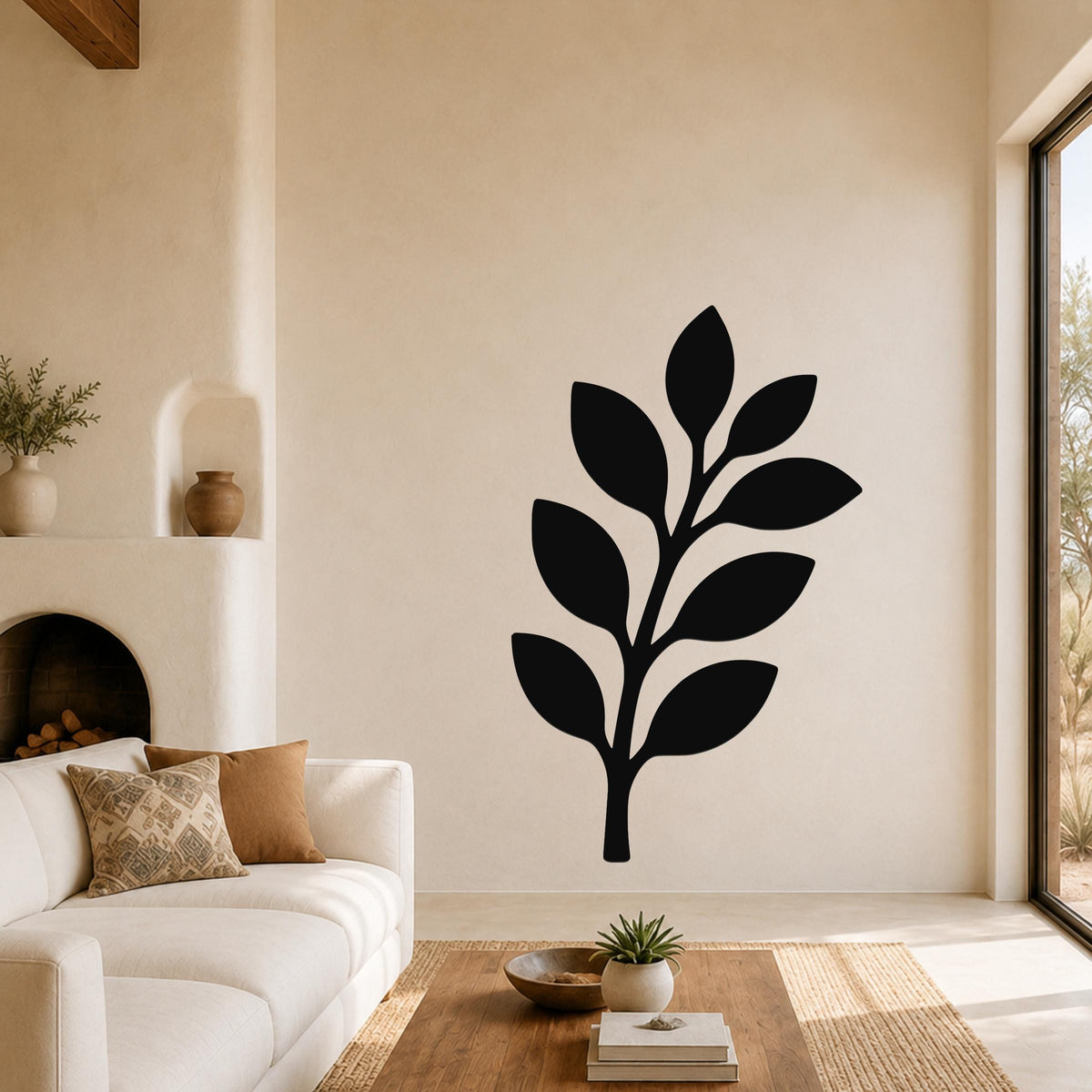 Black metal olive branch wall art with leaf cutouts, mounted on a living room wall above a sofa.