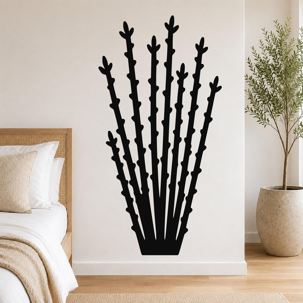 Black metal ocotillo wall art with tall, branching cutouts, mounted on a bedroom wall above a bed.