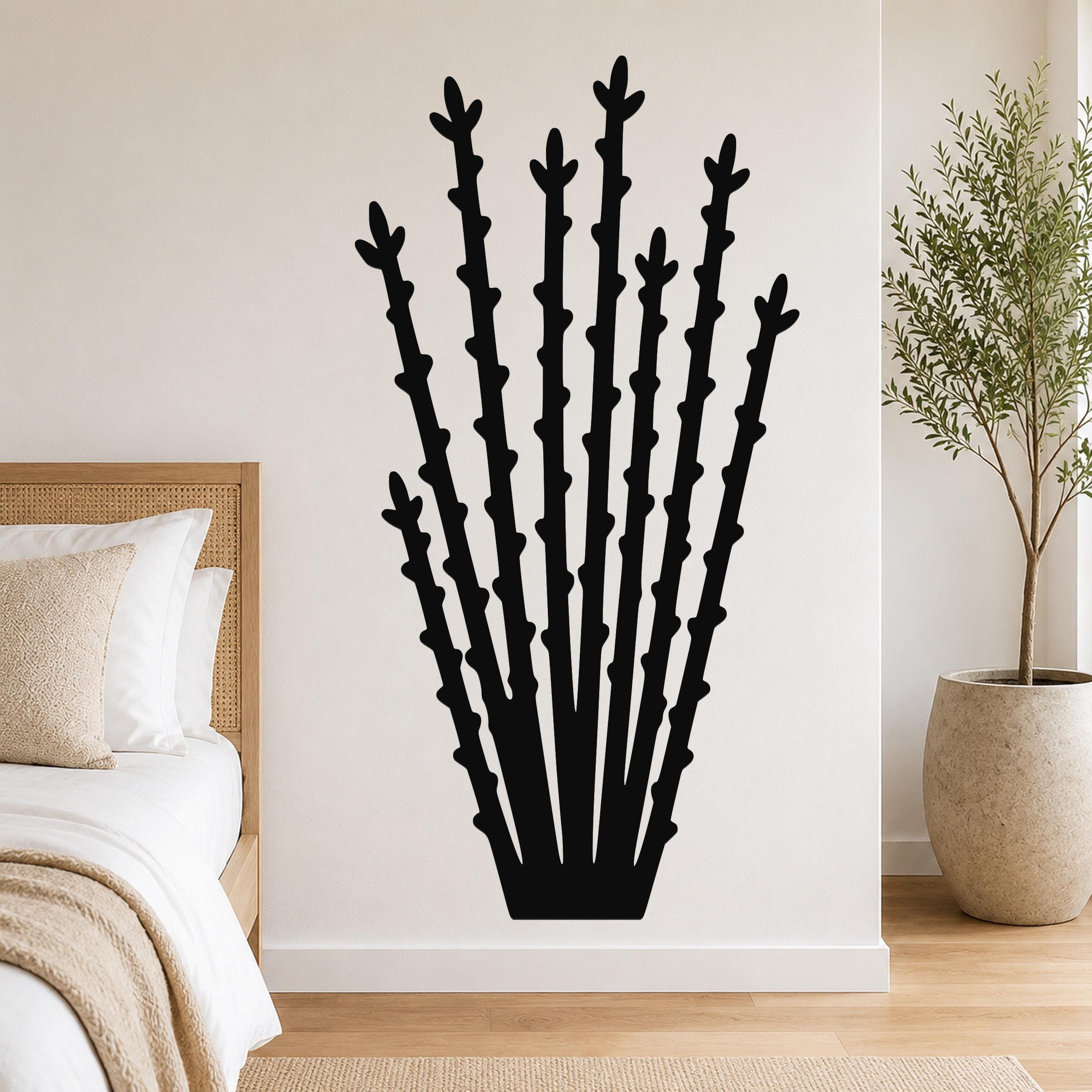 Black metal ocotillo wall art with tall, branching cutouts, mounted on a bedroom wall above a bed.