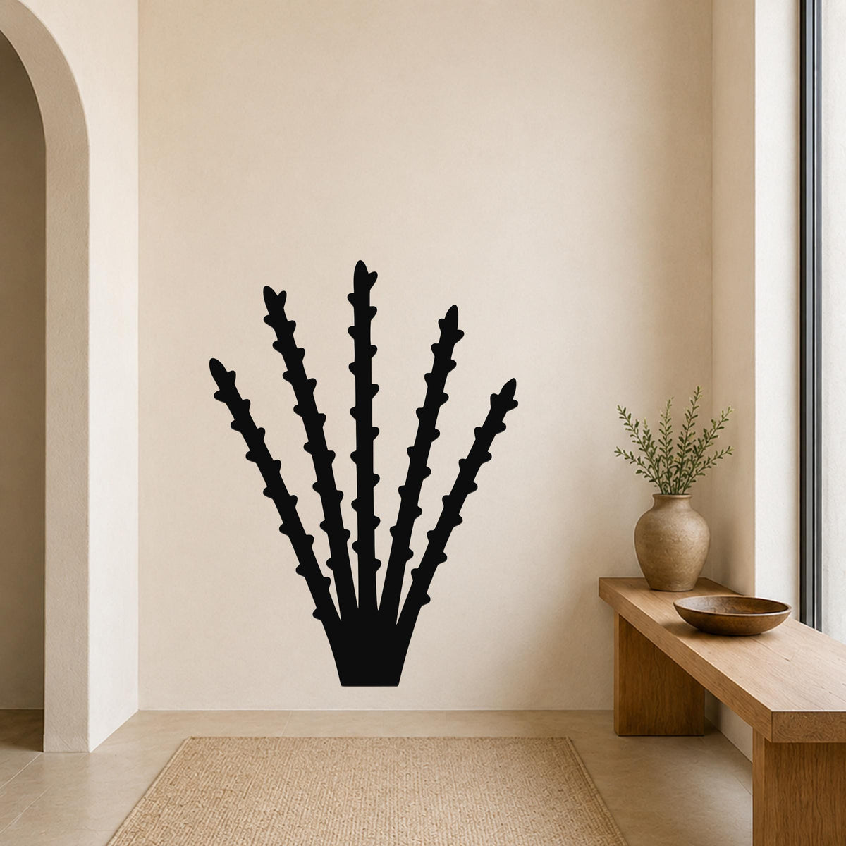 Black metal ocotillo wall art with spiky branch cutouts, mounted on a beige wall above a wooden bench in a living room.